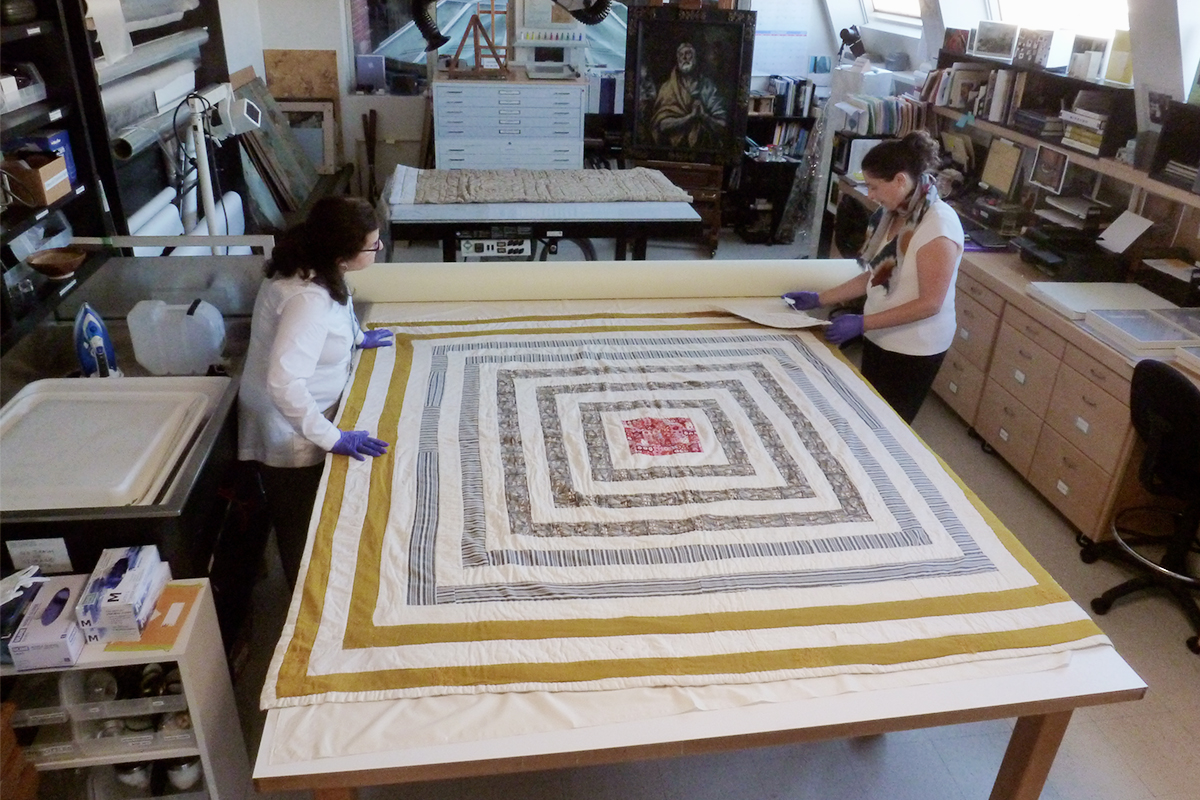 Conservators look at a quilt