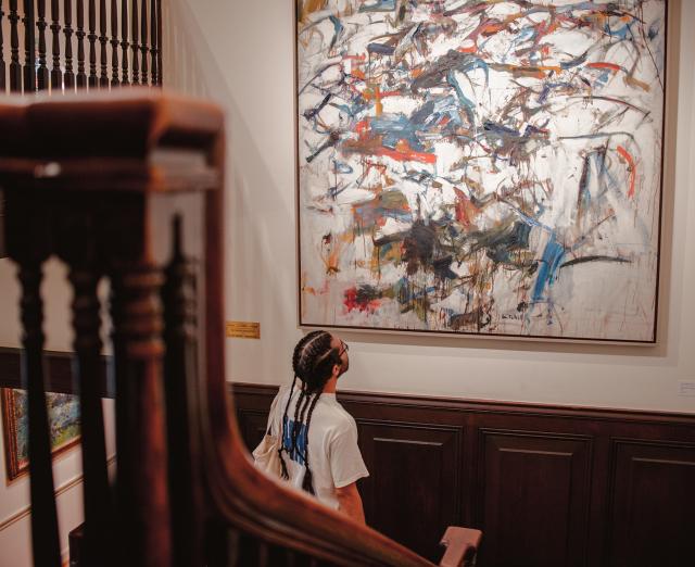 Visitor looking at Joan Mitchell painting in House Stairwell