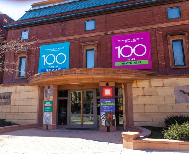 Photo of the main entrance of The Phillips Collection with blue and pink banners with "100" on them