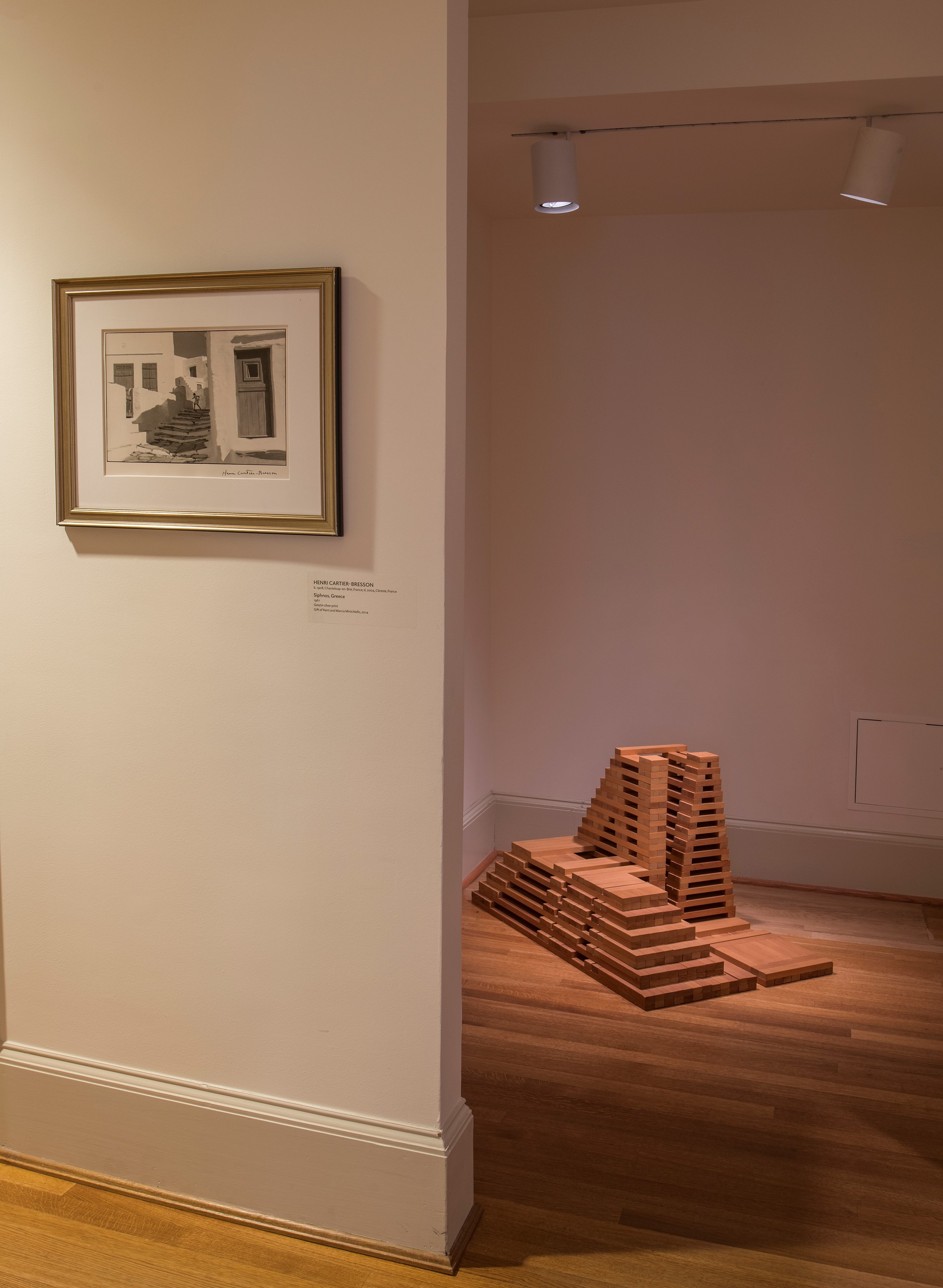 installation view of black and white photo with wood block sculpture around corner