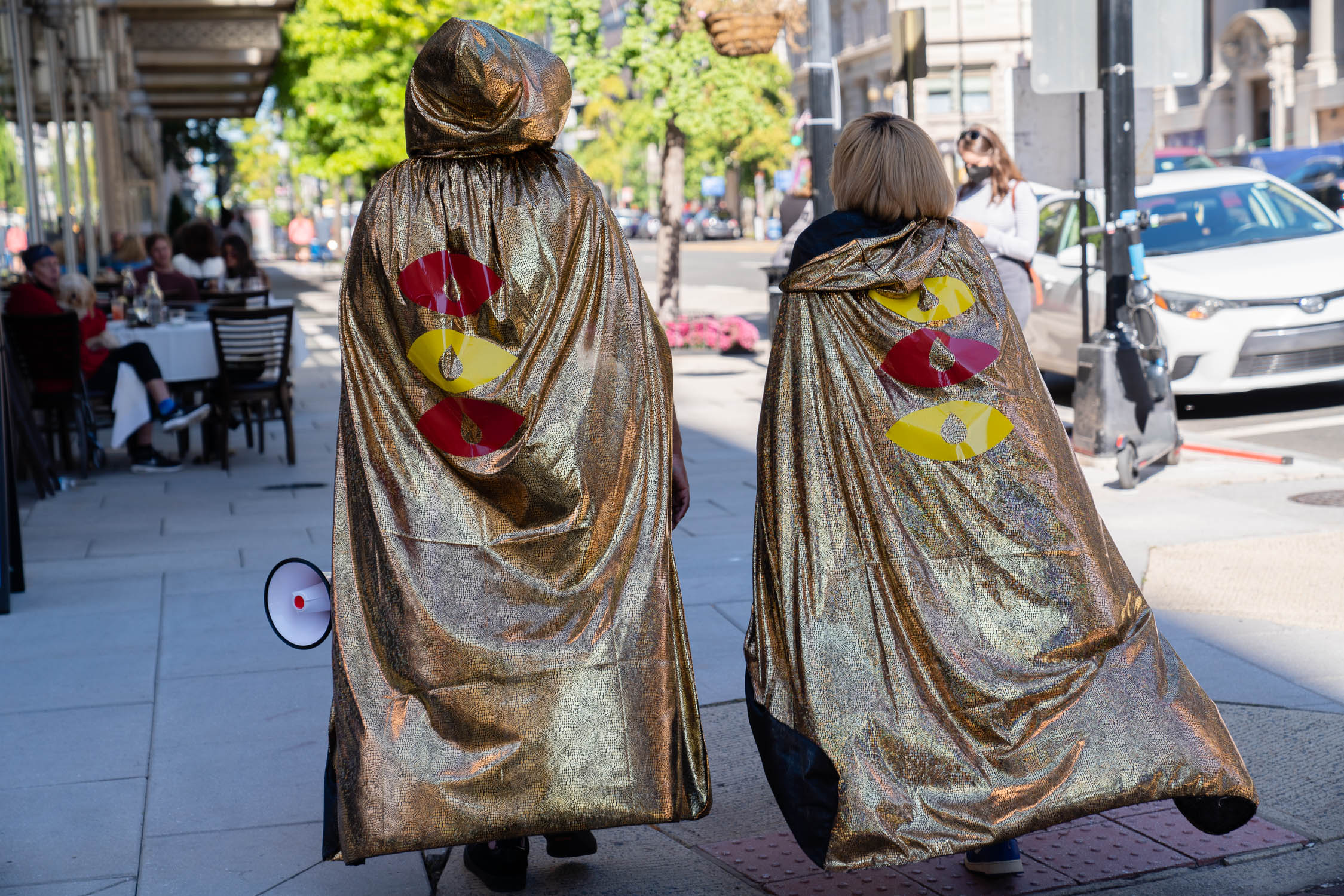 Photograph of two people wearing gold capes