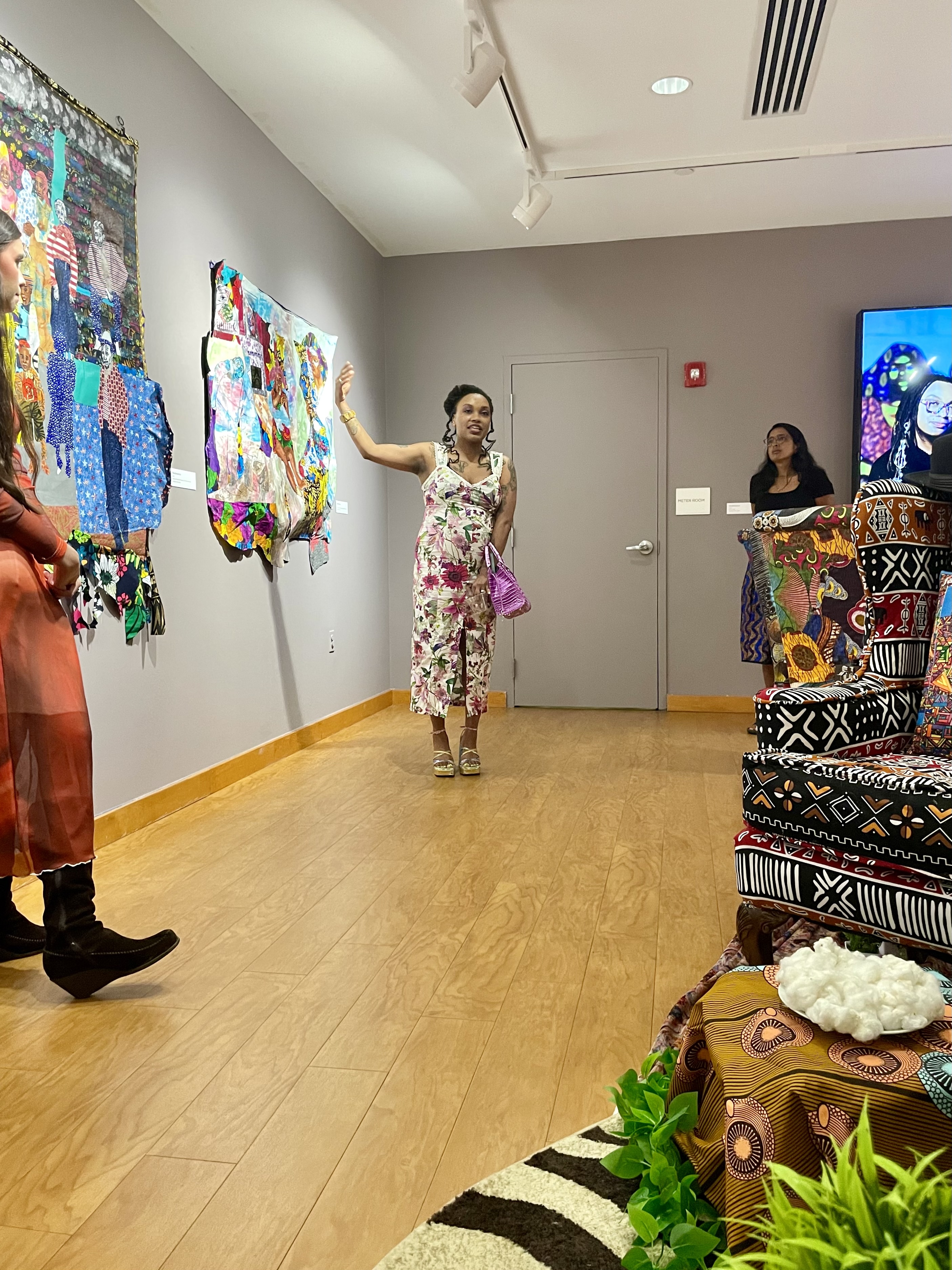 Zsudayka Nzinga at her exhibition opening pointing to one of her artworks on view