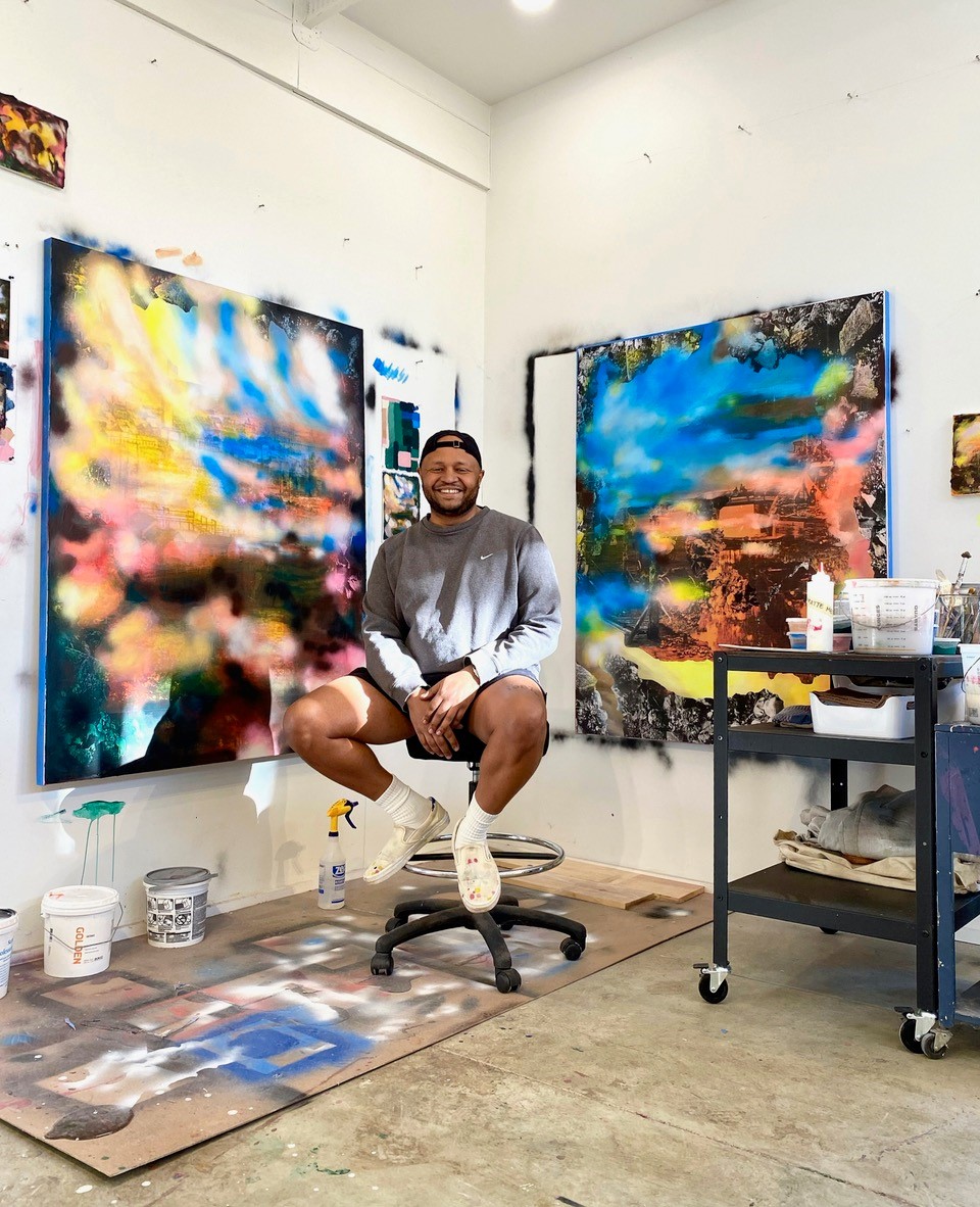 Photograph of Rush Baker sitting in his studio with his artwork