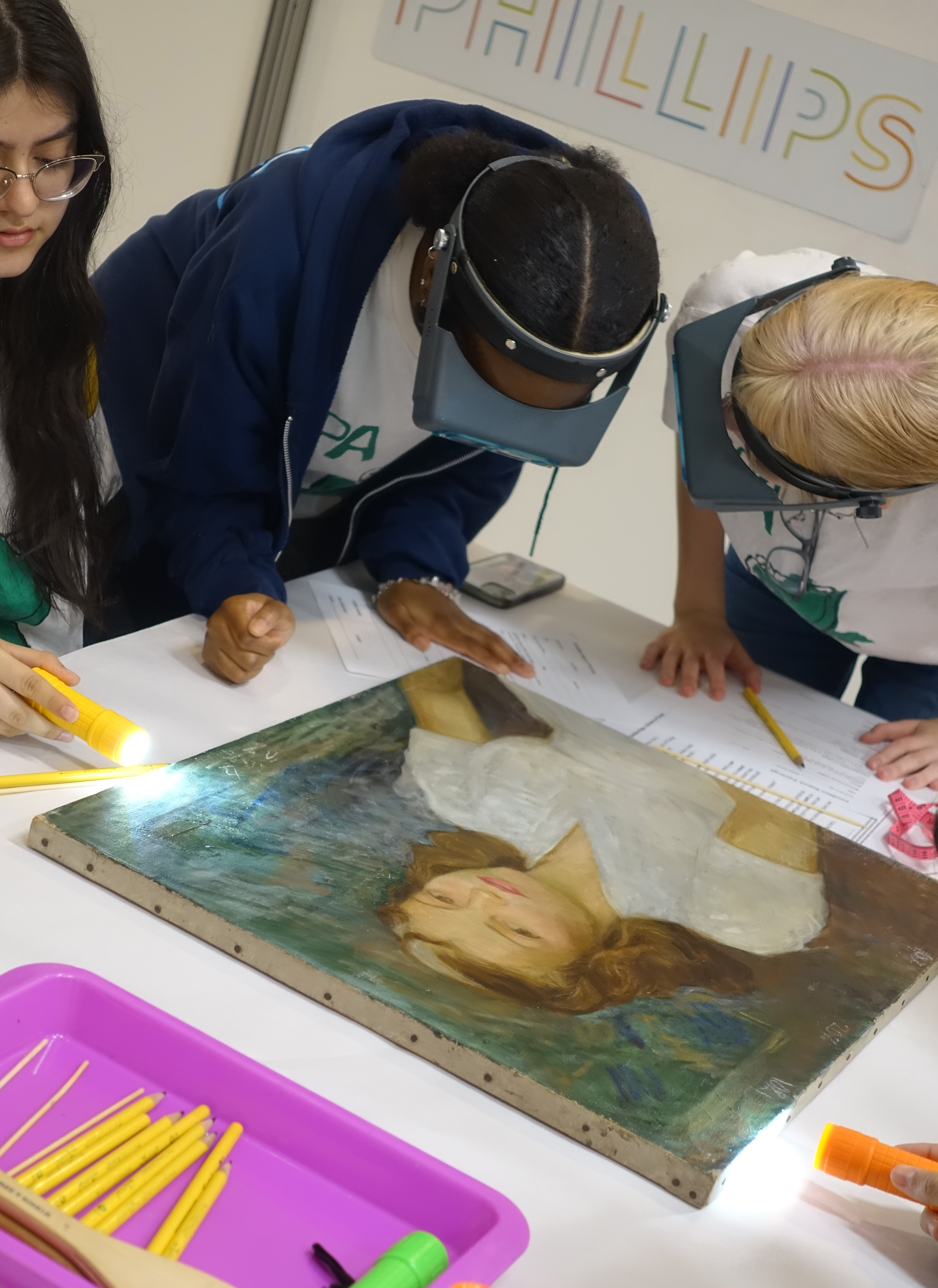 Three high school students examining an artwork in the art workshop