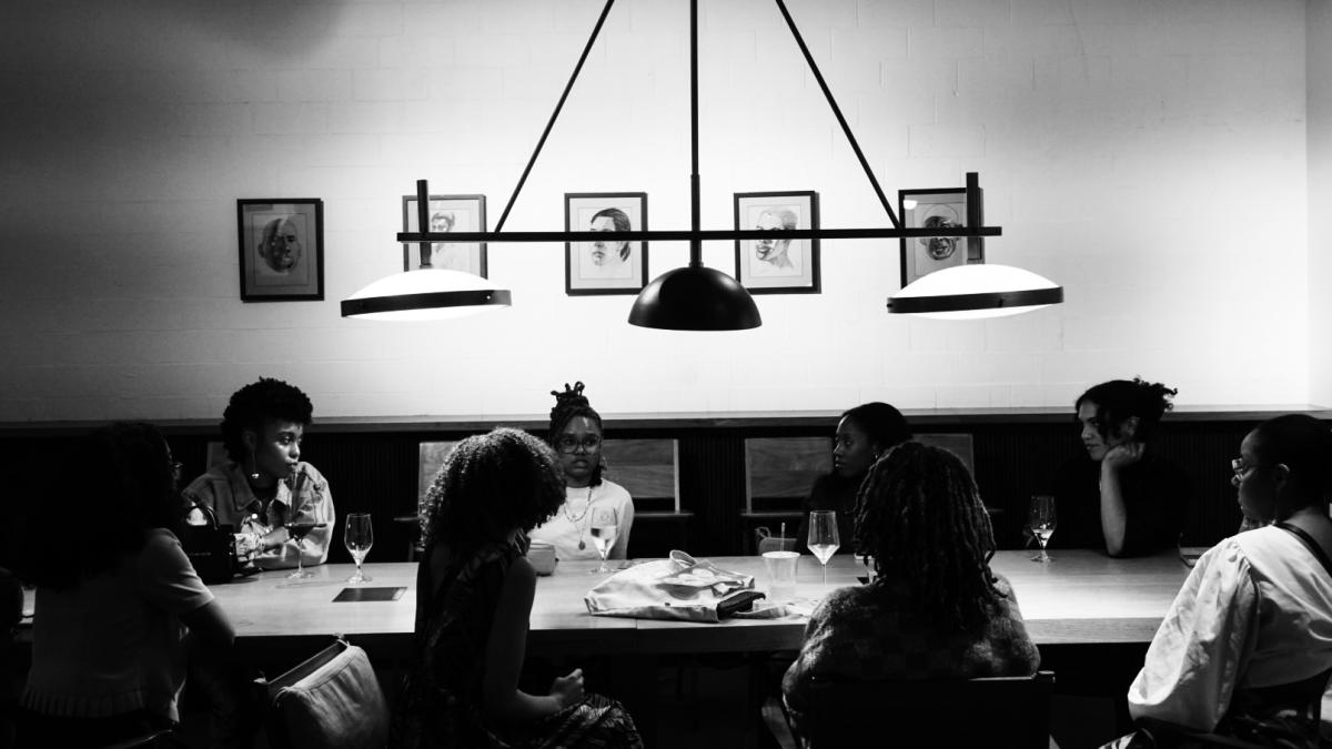 Black and white photograph of 8 people sitting at a table