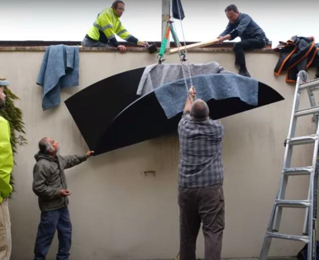 Group of people using a crane to lift Ellsworth Kelly's sculpture in the courtyard