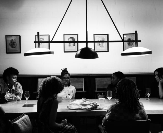 Black and white photograph of 8 people sitting at a table