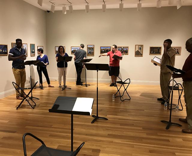 From left to right: Desmond Bing, Nora Achrati, Natalie Graves Tucker, Jeff Allin, Derek Goldman (director), James Johnson, and Craig Wallace. Rehearsing Terrance Arvelle Chisholm’s “In Constant Pursuit” inspired by Panel no. 3: From every southern town migrants left by the hundred to travel north.