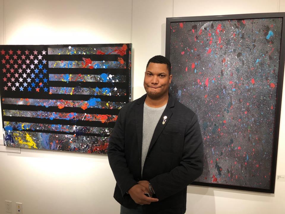 Photo of Zach Herrick with two pieces of artwork created through American Heroes HeART
