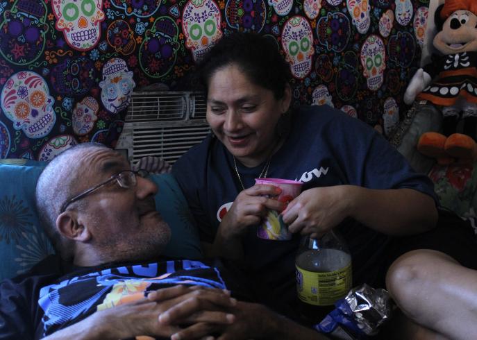 Photograph of a man and woman smiling sitting close to each other on a couch