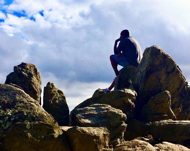 Photograph of a man sitting on boulders, deep in thought