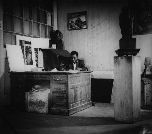 Jacob Lawrence sitting at his studio desk