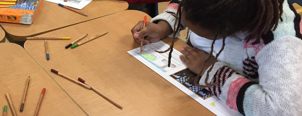 Color photograph of student sitting at a desk creating a storyboard using Lawrence's Migration Series panels