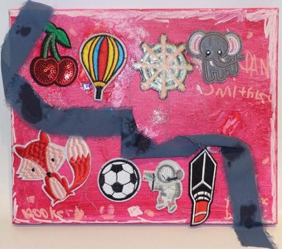 Pink painted canvas with stickers and a ribbon of fabric.