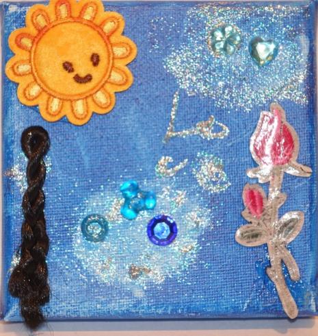 Blue painted canvas with a sun sticker and gems.