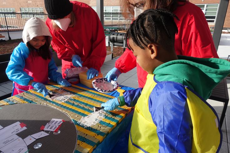 Students grouting mosaic tiles.