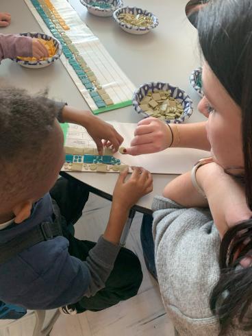 Phillips staff helps student place tile on mosaic.