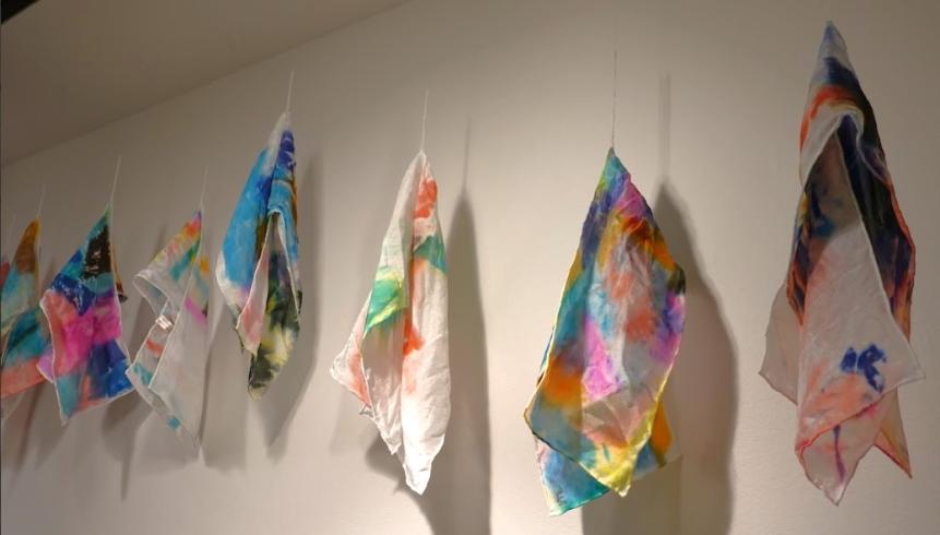 6 silk scarves dyed in various colors displayed from the ceiling.