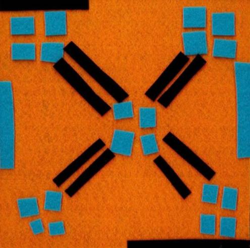 Geometric felt shapes in blue, orange, and black.